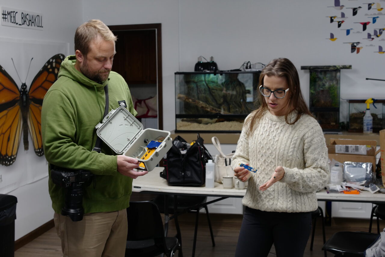 A man holds a FieldKit station with no modules installed next to a woman holding a FieldKit module explaining the modularity